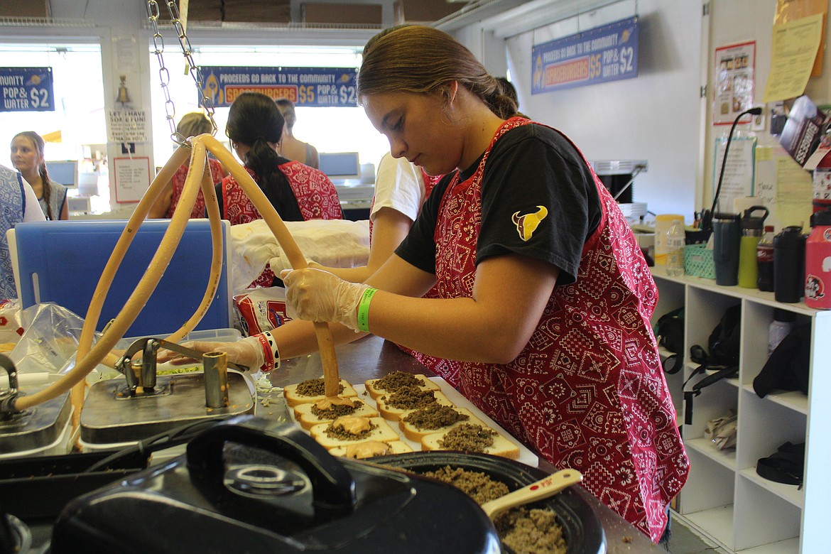 Ally Hindman of the Moses Lake High School cheer team adds the special sauce at the Spaceburger booth Thursday.