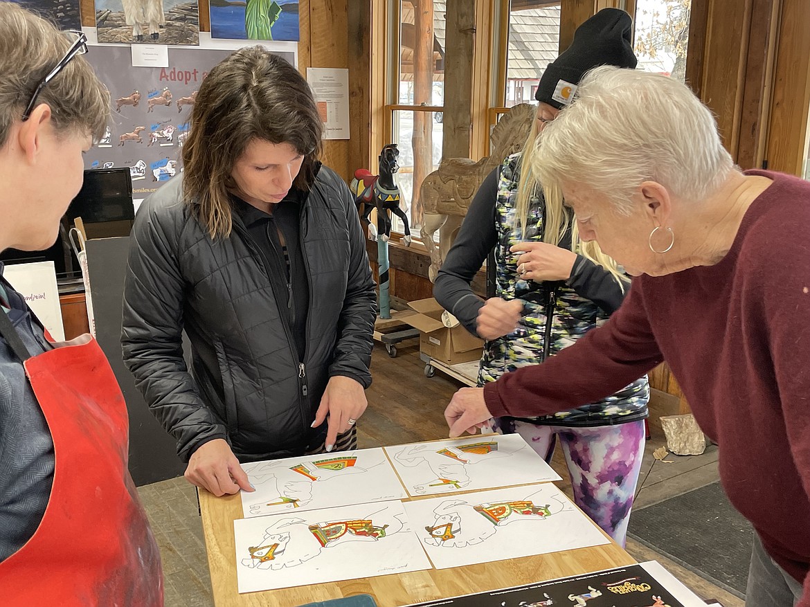 Reno Hutchison, center, talks with Meg Marchiando and Gabe Gabel about the color scheme for some of the ponies for the Carousel of Smiles. Hutchison, who launched the nonprofit with her husband Clay following their purchase of the 1920 Allan Herschel carousel in 2000, announced the lease and option to purchase the former Co-Op Gas & Supply building on Church Street as the potential future home of the carousel.