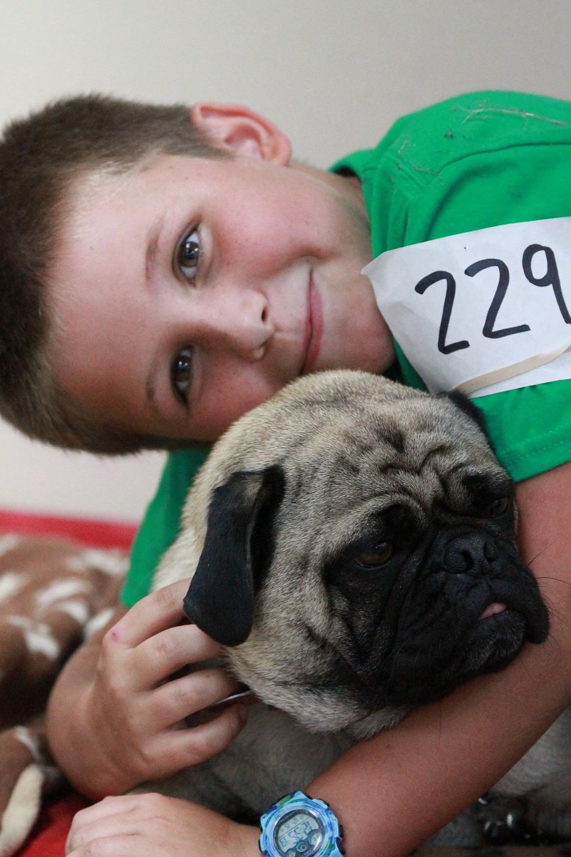 Josiah Spees hugs his pug, Otis as other members of the Happy Tails 4-H group make their rounds around the ring in the obedience competition. Otis is 3 years old.