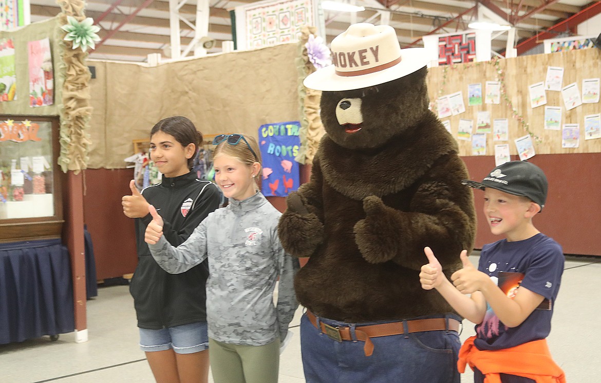 Charley Martin, Sylvia Nees and Calvin Nees give a thumbs up to meeting Smokey Bear at the Bonner County Fair on Friday.