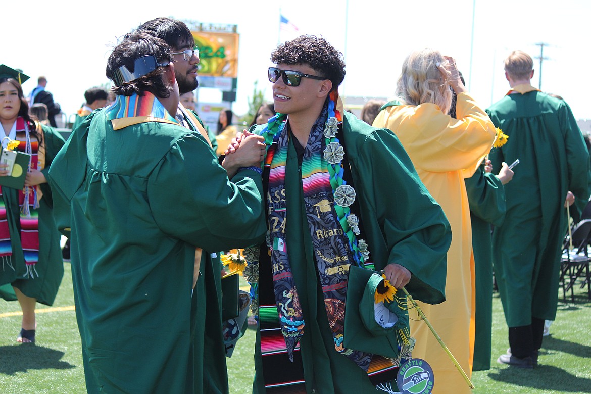 Newly graduated Quincy seniors exchange a handshake after the June ceremony. The class of 2024 was larger than the incoming kindergarten class, and enrollment in primary grades is trending down, which were among the factors that led Quincy School District officials to project little change enrollment for the 2024-25 school year.