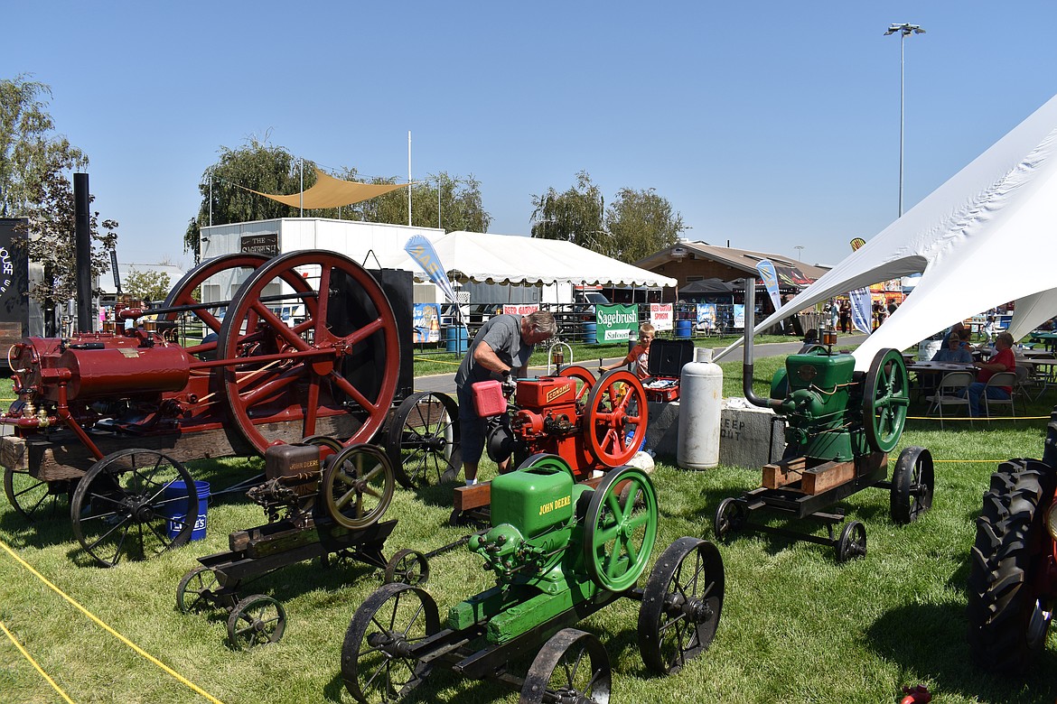 Mike Phelps feeds fuel into an engine displayed by the Columbia Basin Antique Power Club at the Grant County Fair Aug. 14.