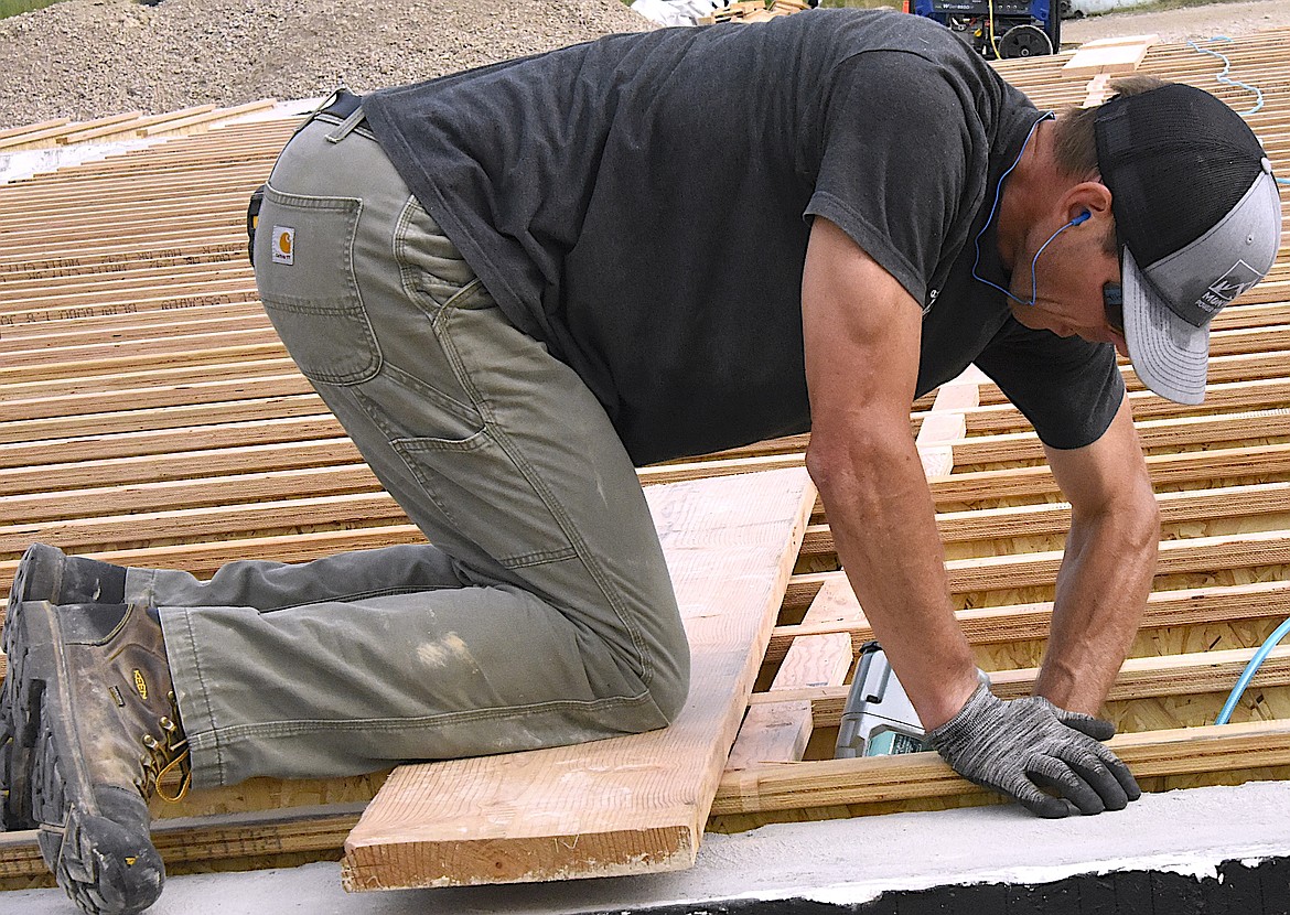 One of the volunteer workers on Jake's House works with a nail gun on the floor joists. (Berl Tiskus/Leader)