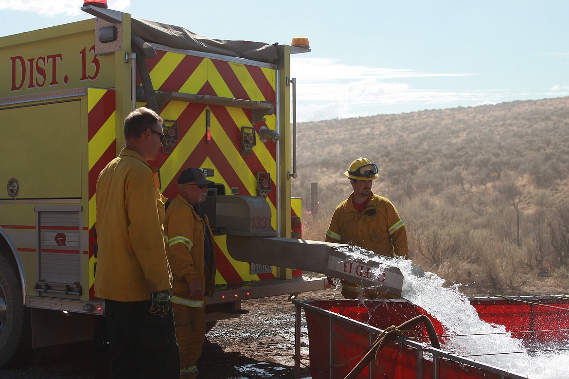 Firefighters from Fire District 13 fill a reservoir of water for the fire outside of Quincy on Overen Road.