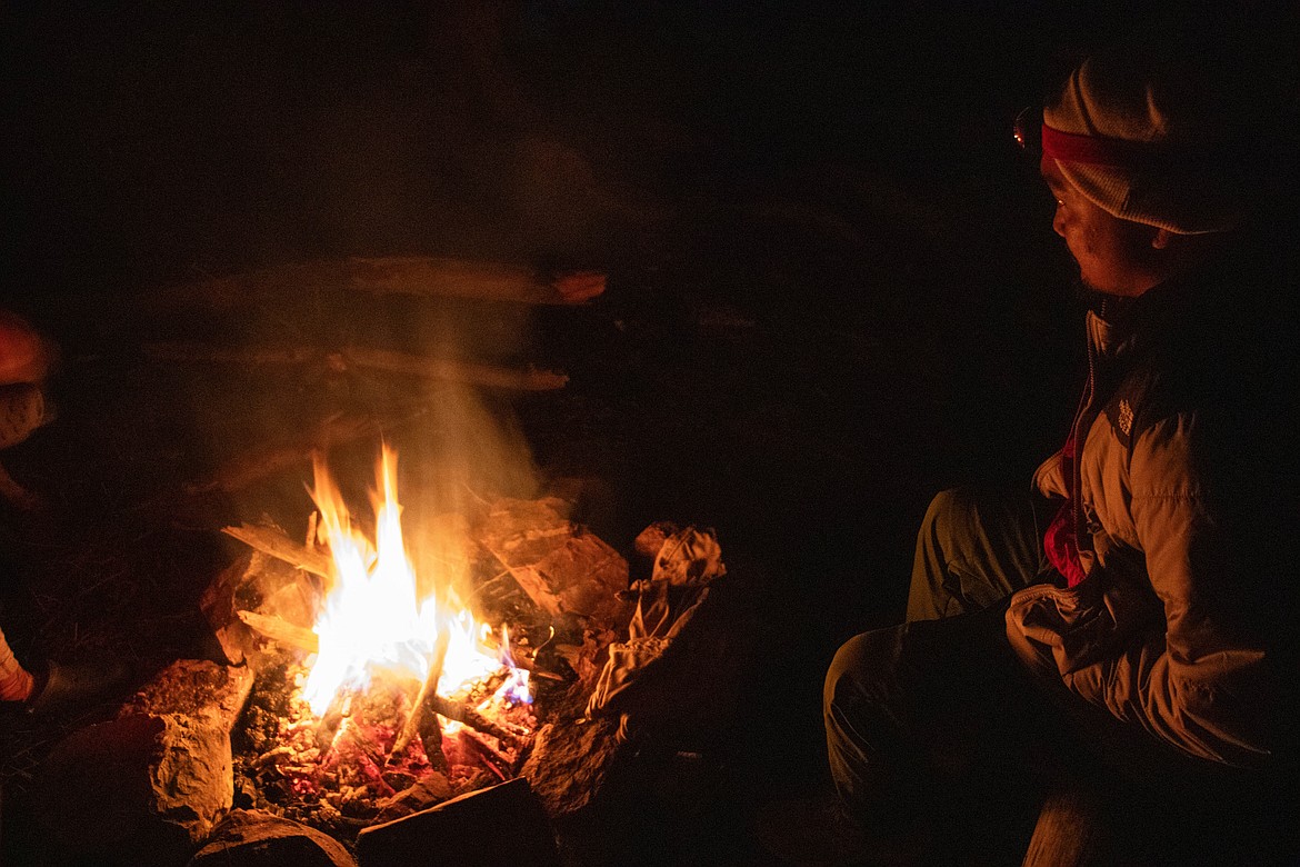 Ron Rydelle Ramos, from Hawaii, sits by a campfire while on a backpacking trip. (Kate Heston/Daily Inter Lake)