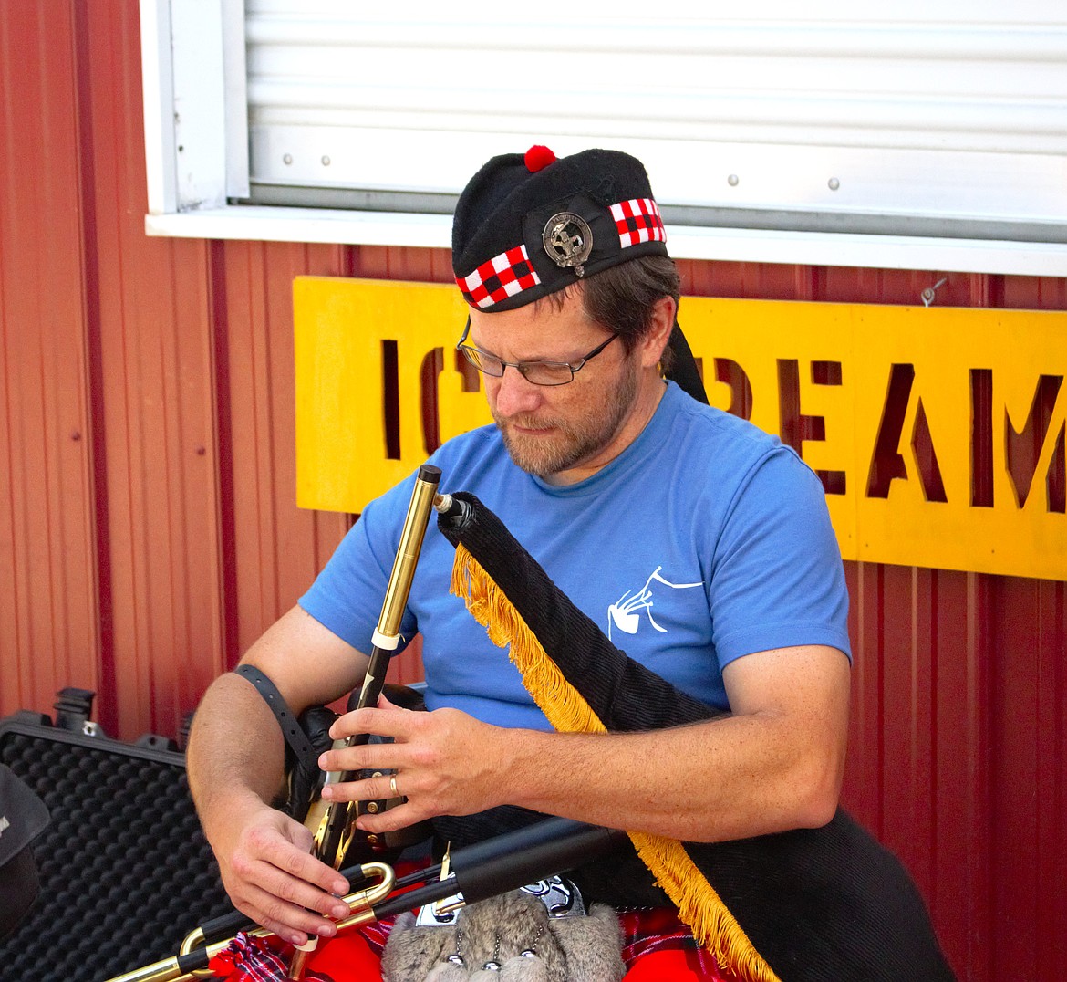 A musician performs the Irish pipe at a booth.