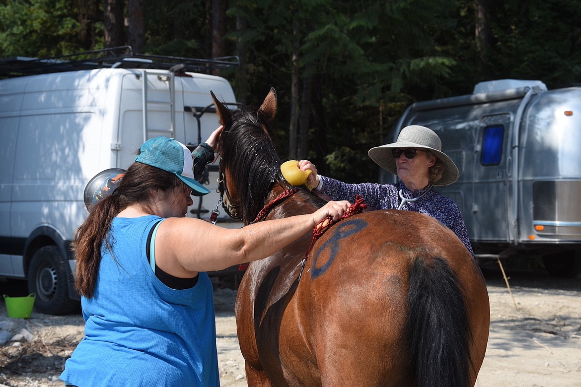 Christina Buehner of Kalispell and Sue McLain of Washington tend to a horse at the Big Sky Memorial Ride Saturday, Aug. 10, 2024. (Scott Shindledecker/The Western News)
