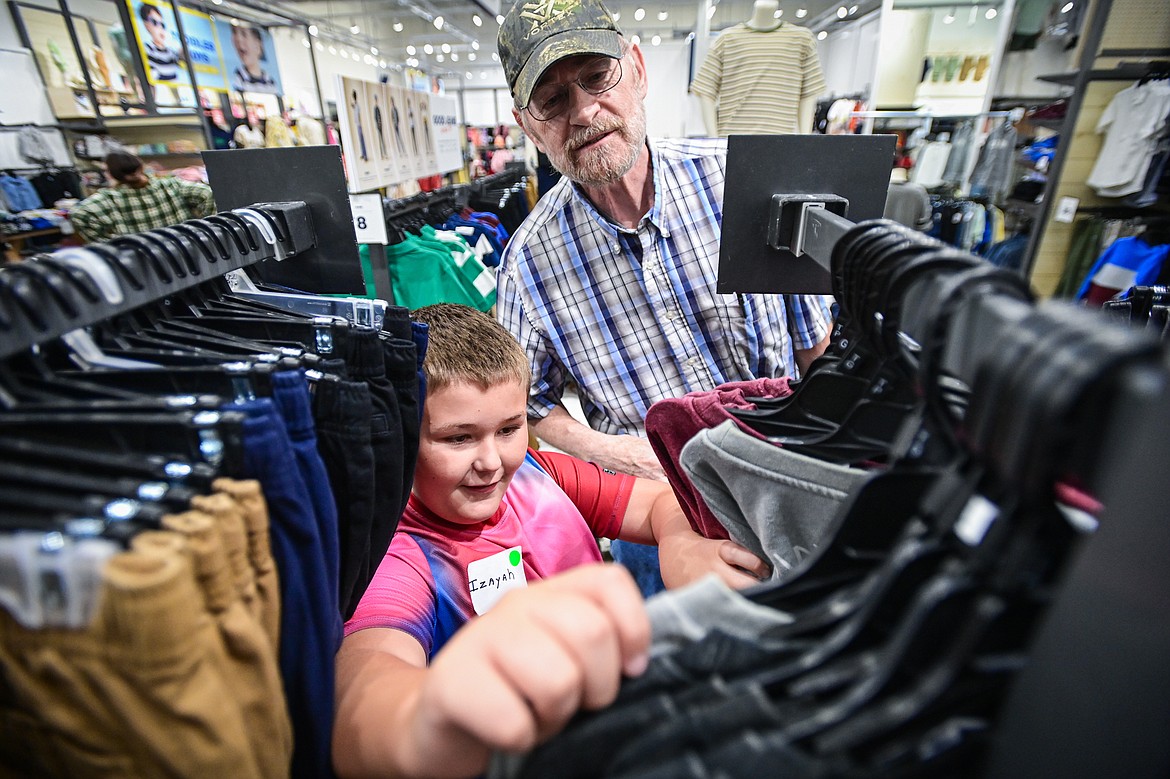 Izayah looks through a rack of sweatshirts as he shops with Pete Arneson during Salvation Army Kalispell's Back to School shopping event at Old Navy on Wednesday, Aug. 21. (Casey Kreider/Daily Inter Lake)