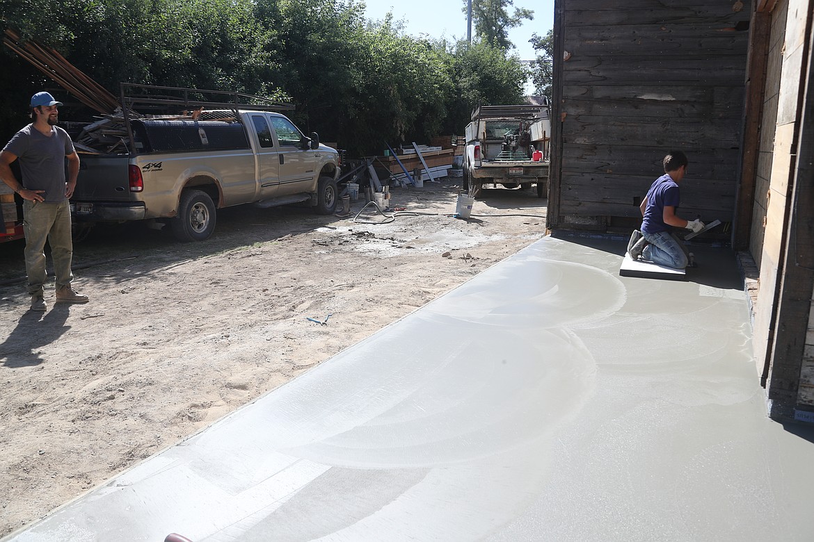 Justin Bernier watches as his son Jonah, 13, works to finish concrete at a Church Street home.