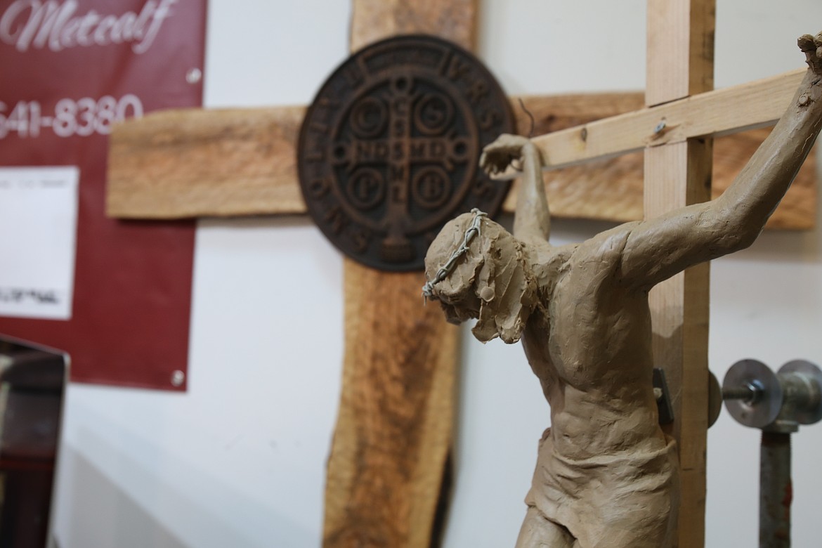 A small-scale version of Cheryl Metcalf's Christ sculpture is seen Thursday morning with the olive wood cross to which the final product will be affixed in the background.