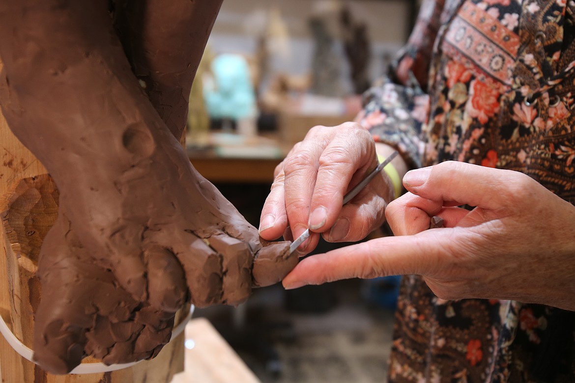 Cheryl Metcalf adds texture Thursday to a toe of the Christ sculpture she has been commissioned to build for a local Catholic family.