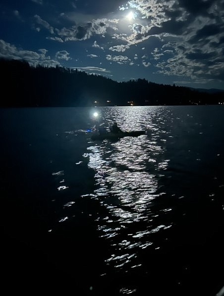 Kim Bowler, with husband Chris Bowler nearby on his kayak, swims in Priest Lake at night during her quest to swim from one end of the lake to the other on Monday.