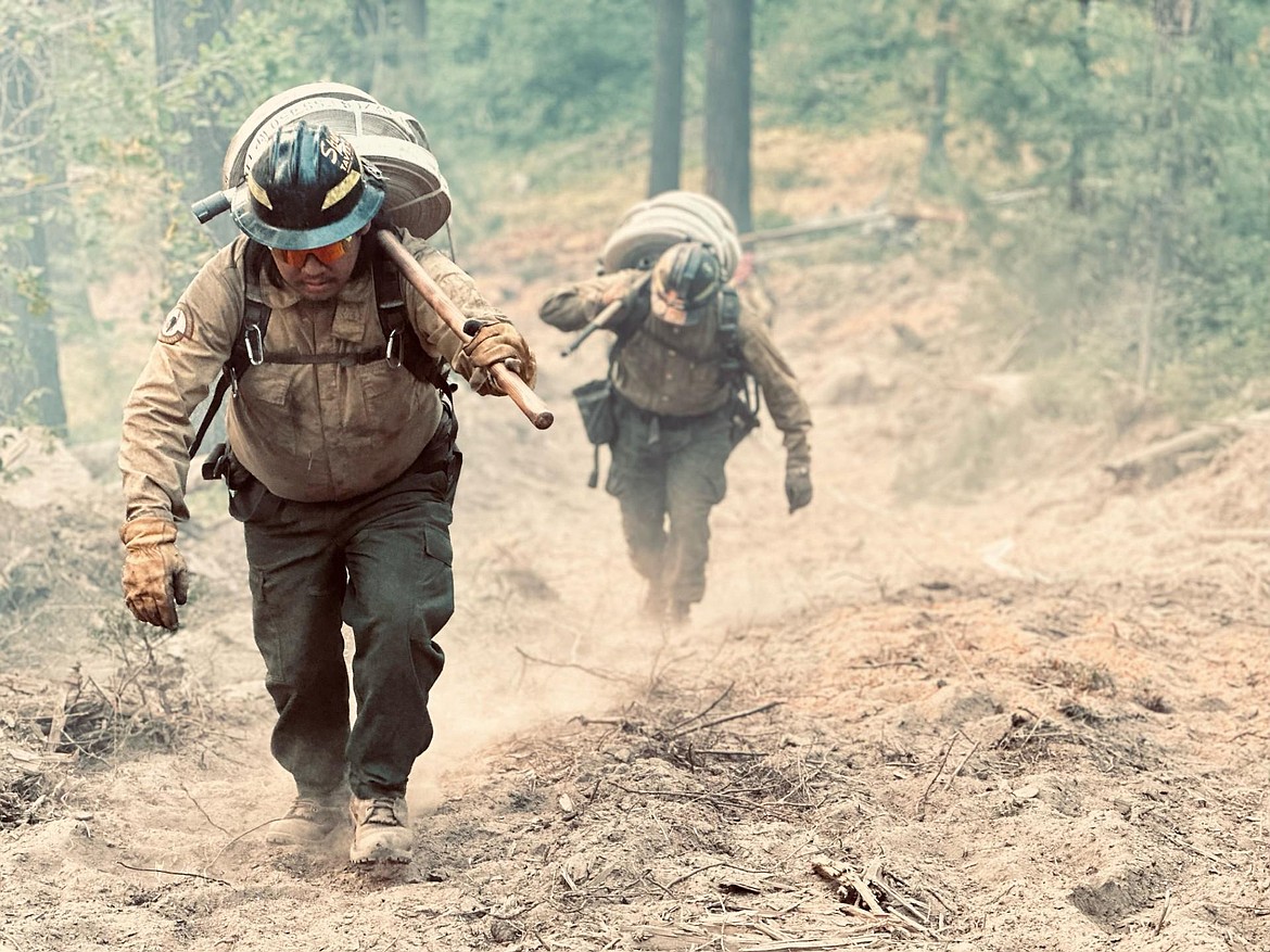 Firefighters pack hose and supplies into the Williams Mine Fire area earlier this month.