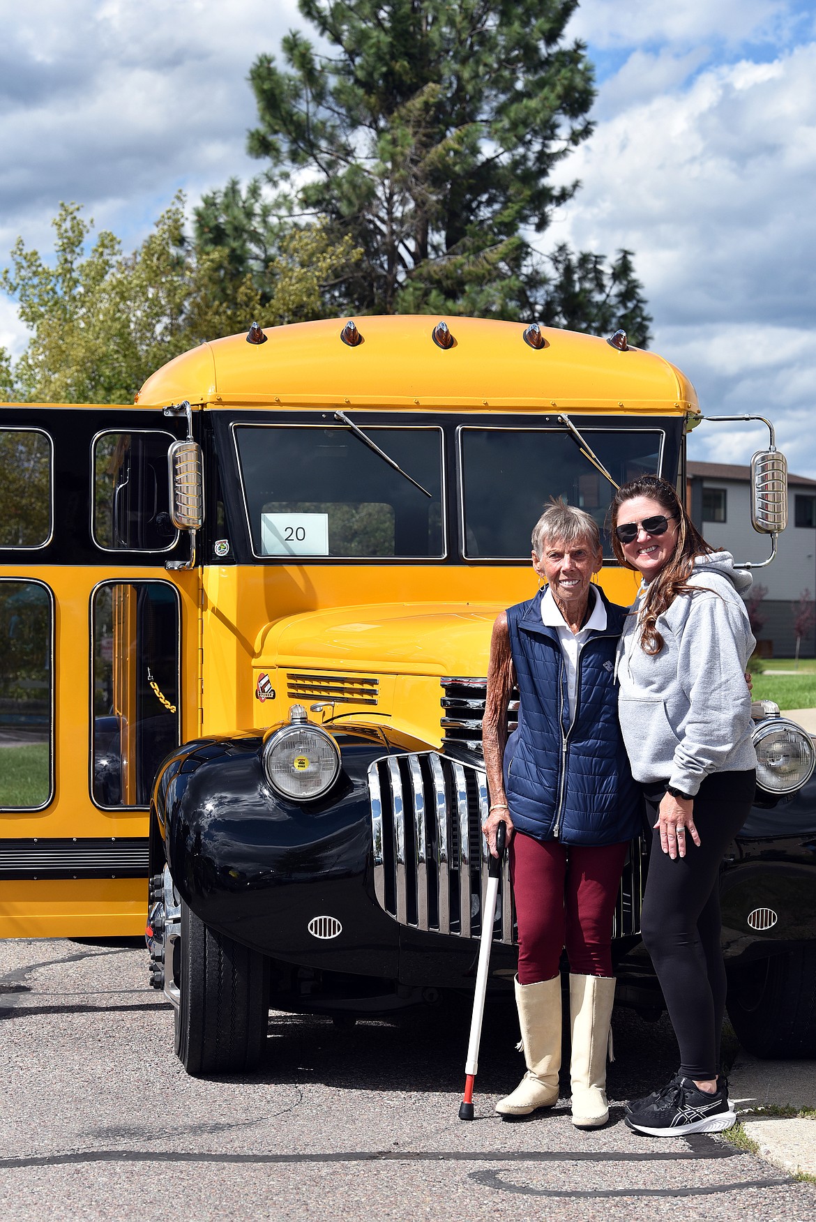 Janice Hale and Staci Ost have a chat in front of a brilliant yellow school bus. Hale worked as a high school tutor and Ost was one of her students. (Julie Engler/Whitefish Pilot)