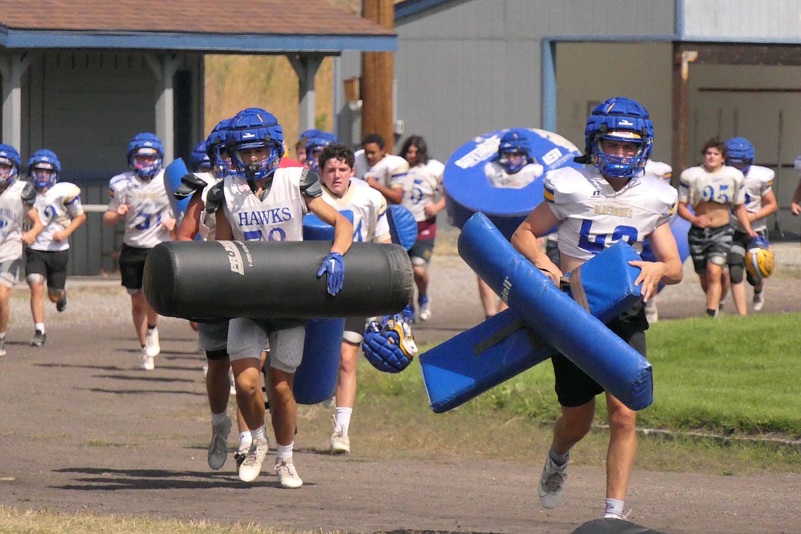 Members of this year's T Falls Blue Hawks football team carry pads and other gear onto the field as they get ready for their season opener this Friday night in Conrad.  (Chuck Bandel/VP-MI)