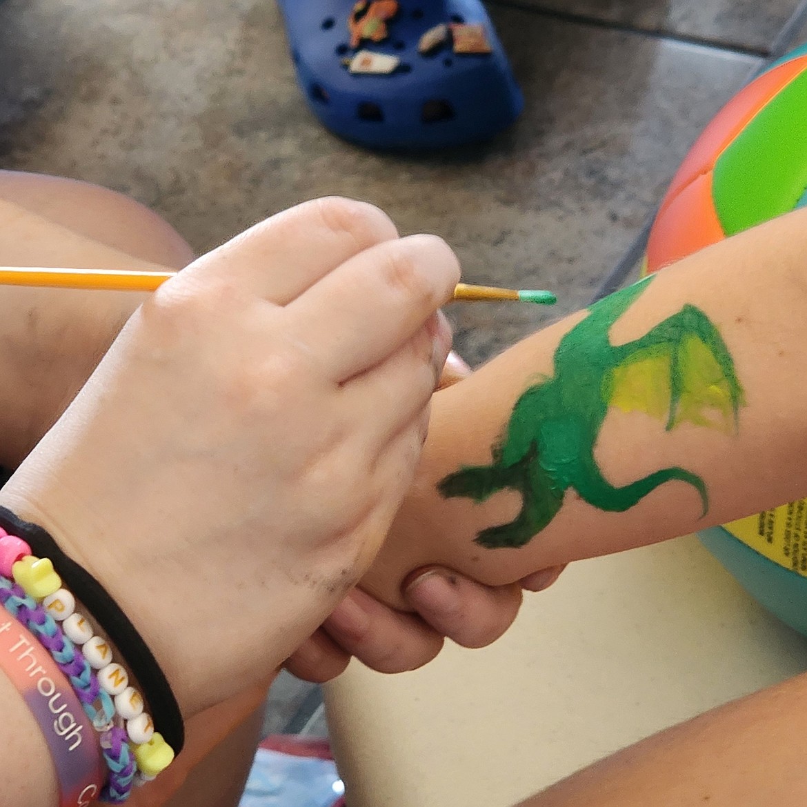 What's a party without face or arm painting? A girl gets a fanciful dragon on her arm for good luck during Mission Valley Aquatics Family Fun Day, held Saturday. (Berl Tiskus/Leader)