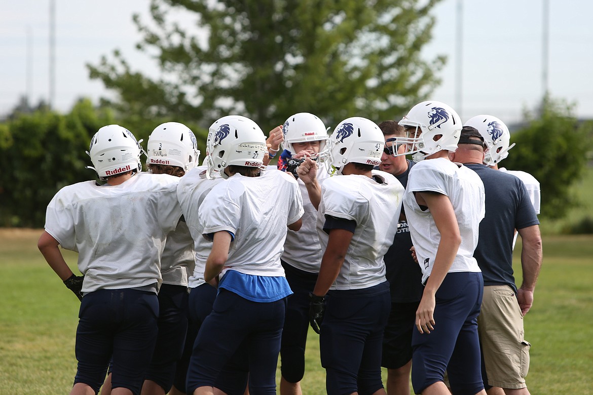 MLCA/CCS players huddle up with coaches at the start of practice on Saturday. The Lions saw their roster numbers decrease from 18 to 12 this season, meaning there will be more players hitting the field on both sides of the football this fall.