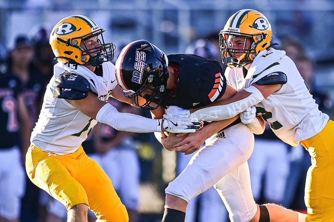 Flathead quarterback Brett Pesola (4) is tackled by a pair of Great Falls CMR defenders on a run in the first half at Legends Stadium on Friday, Aug. 30. (Casey Kreider/Daily Inter Lake)