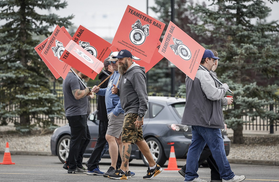 Teamsters Canada Rail Conference members walk a picket line at the CPKC headquarters in Calgary, Alberta, Thursday, Aug. 22, 2024. (Jeff McIntosh/The Canadian Press via AP)