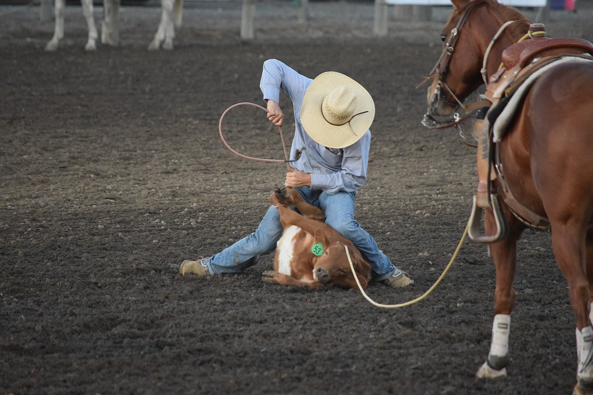 A cowboy ties his calf down during the calf roping event. The calf must stay tied for six seconds for qualifying time.