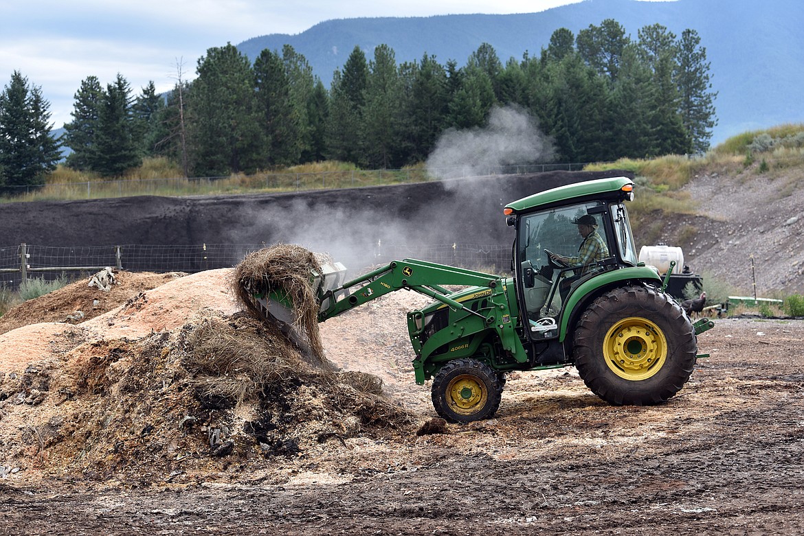 Steam rises as Anastacia Rodak moves piles of organic material in the process of being composted at the Dirt Rich Compost facility. (Julie Engler/Whitefish Pilot)