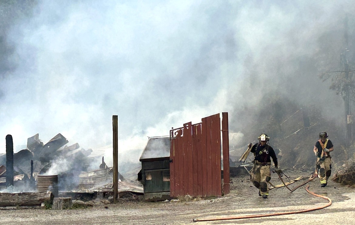 Firefighters carry hoses outside the Wolf Lodge Steakhouse on Monday.