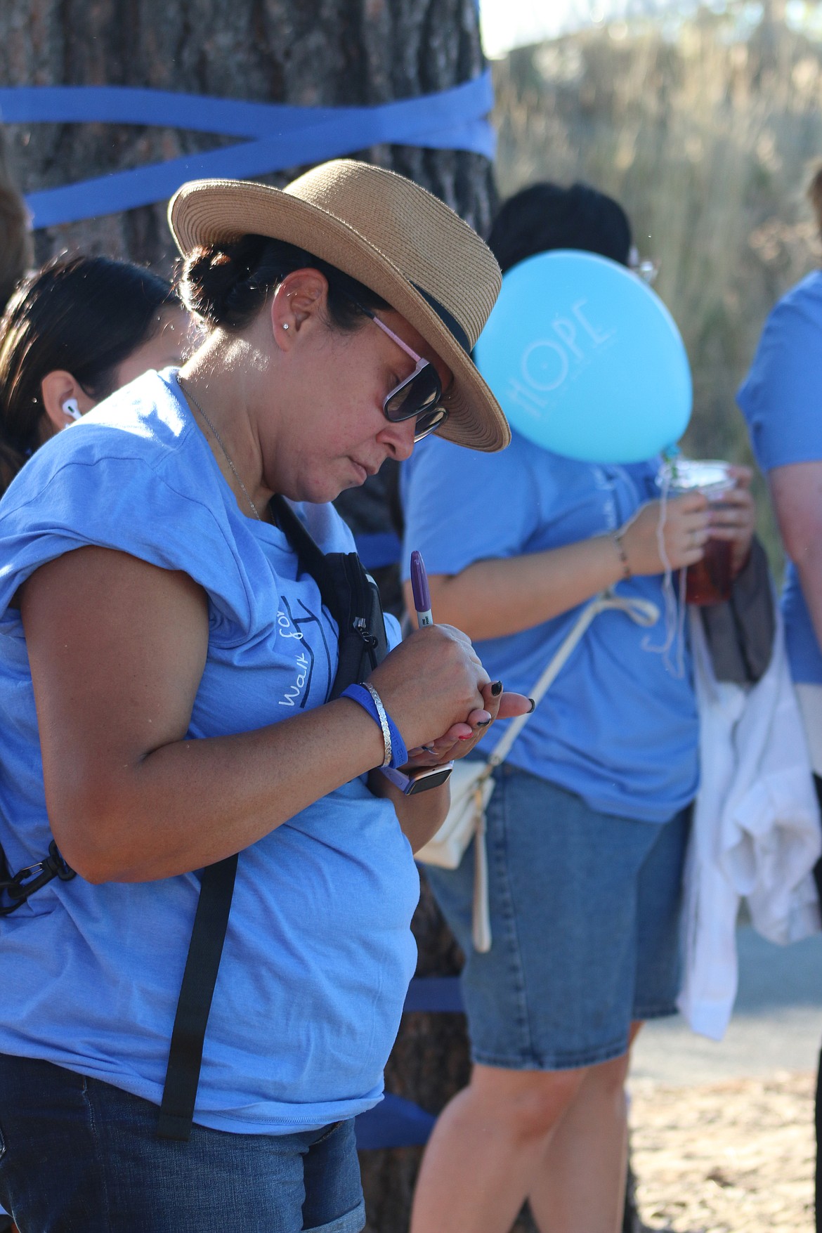 A Walk for HOPE participant writes a message on a stone as she takes part in the Walk for HOPE on Sunday.