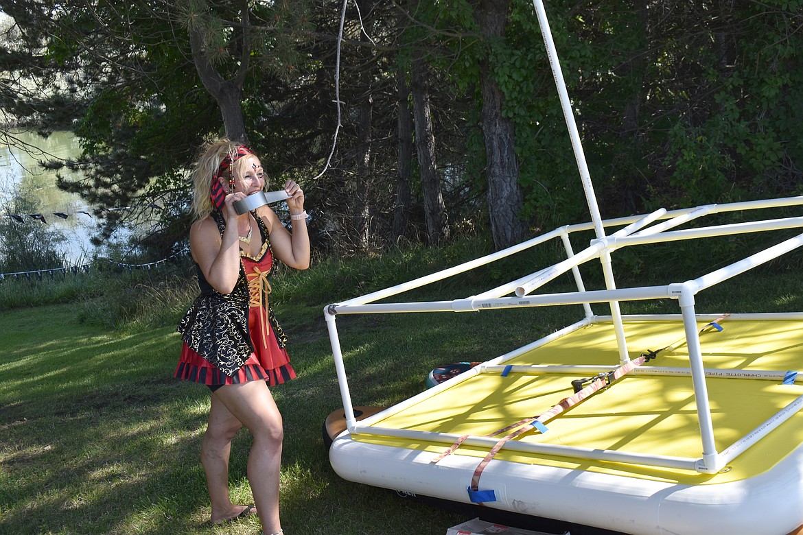 Shawna Sloane bites off a piece of duct tape while assembling her boat, the Risen Indeed, for the Pirate Regatta Sunday at Camas Cove Cellars.