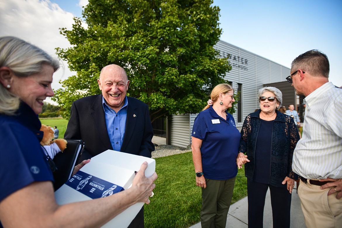 Kalispell businessman Paul Wachholz smiles while receiving a gift from Laura McCollum, head of school at Stillwater Christian School, during a back-to-school open house where it was announced Wachholz was donating $5 million to build an addition on Tuesday, Sept. 3. (Casey Kreider/Daily Inter Lake)