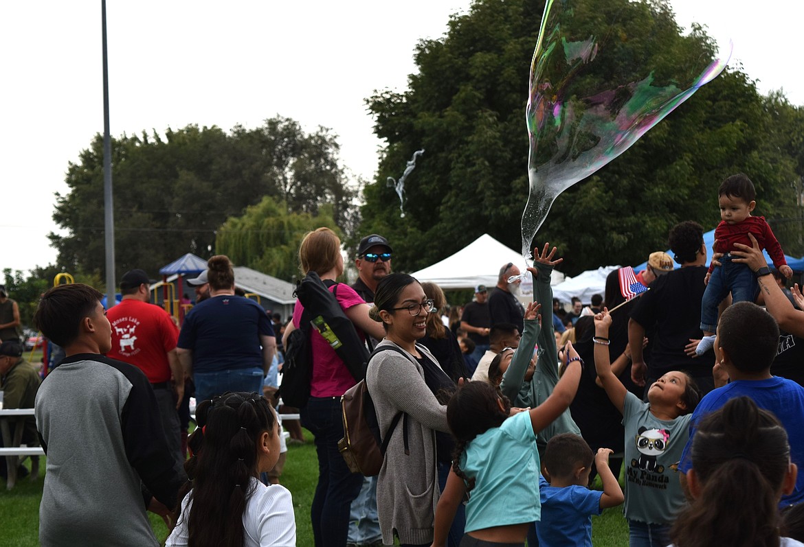 Children try to catch oversized bubbles at Warden Park at the Warden Community Days Monday.