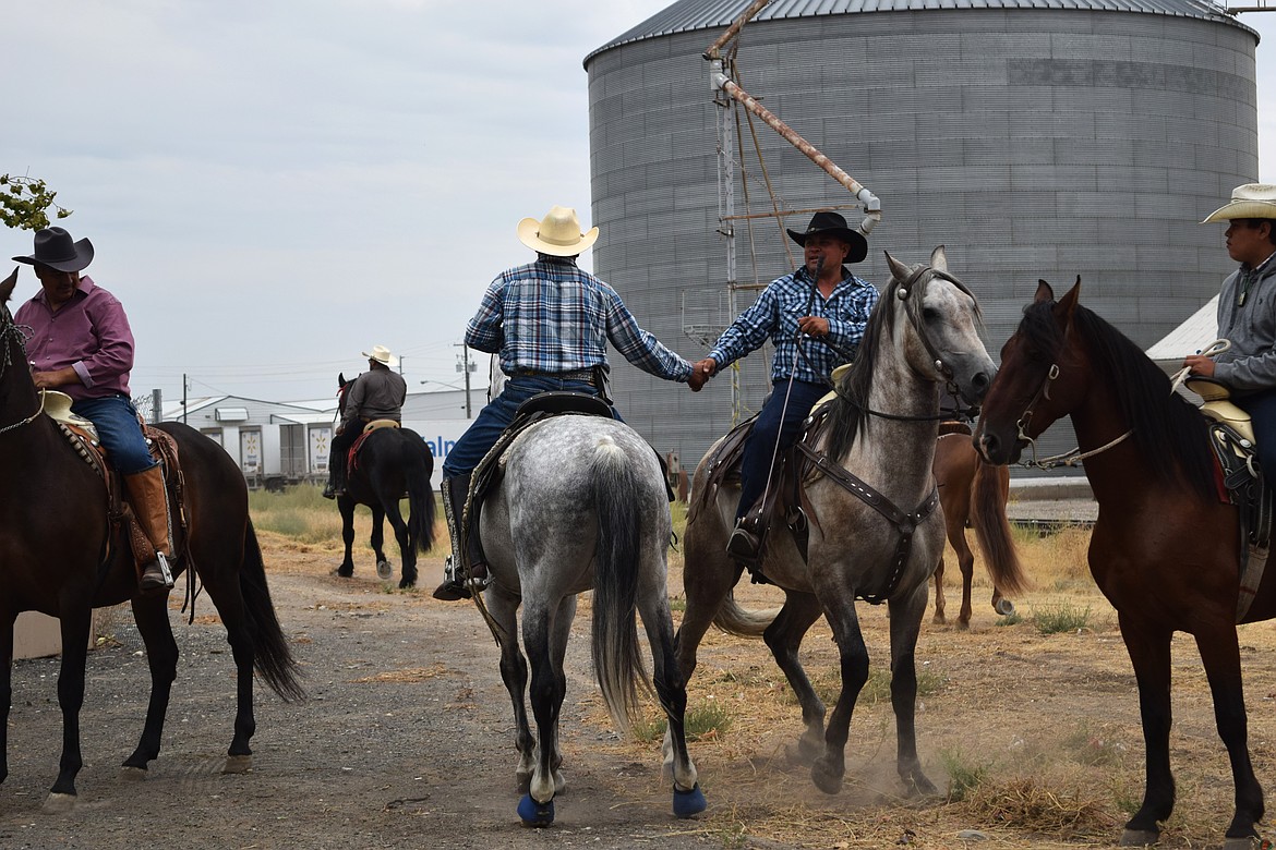 Two cowboys shake hands before the start of the parade in Warden Monday. More than 20 people rode horses during the parade.