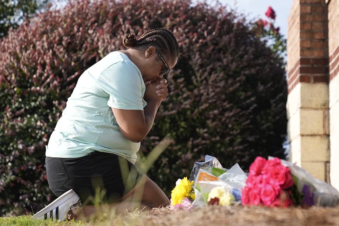 Linda Carter, of Grayson, Ga., kneels near Apalachee High School to place flowers as she mourns for the slain students and teachers on Thursday, Sept. 5, 2024, in Winder, Ga. (AP Photo/Brynn Anderson)