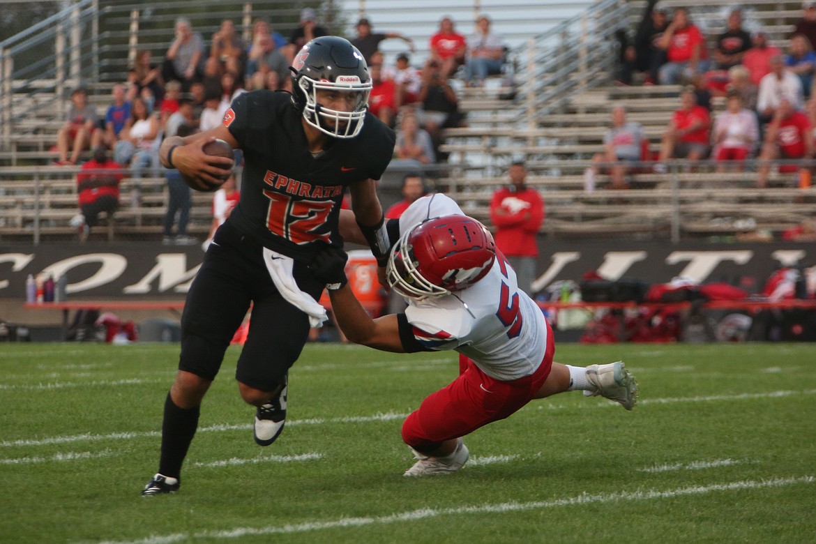 Ephrata quarterback Brady Hendrick, in black, stiff-arms a Prosser defender while fighting for extra yards in the first quarter.