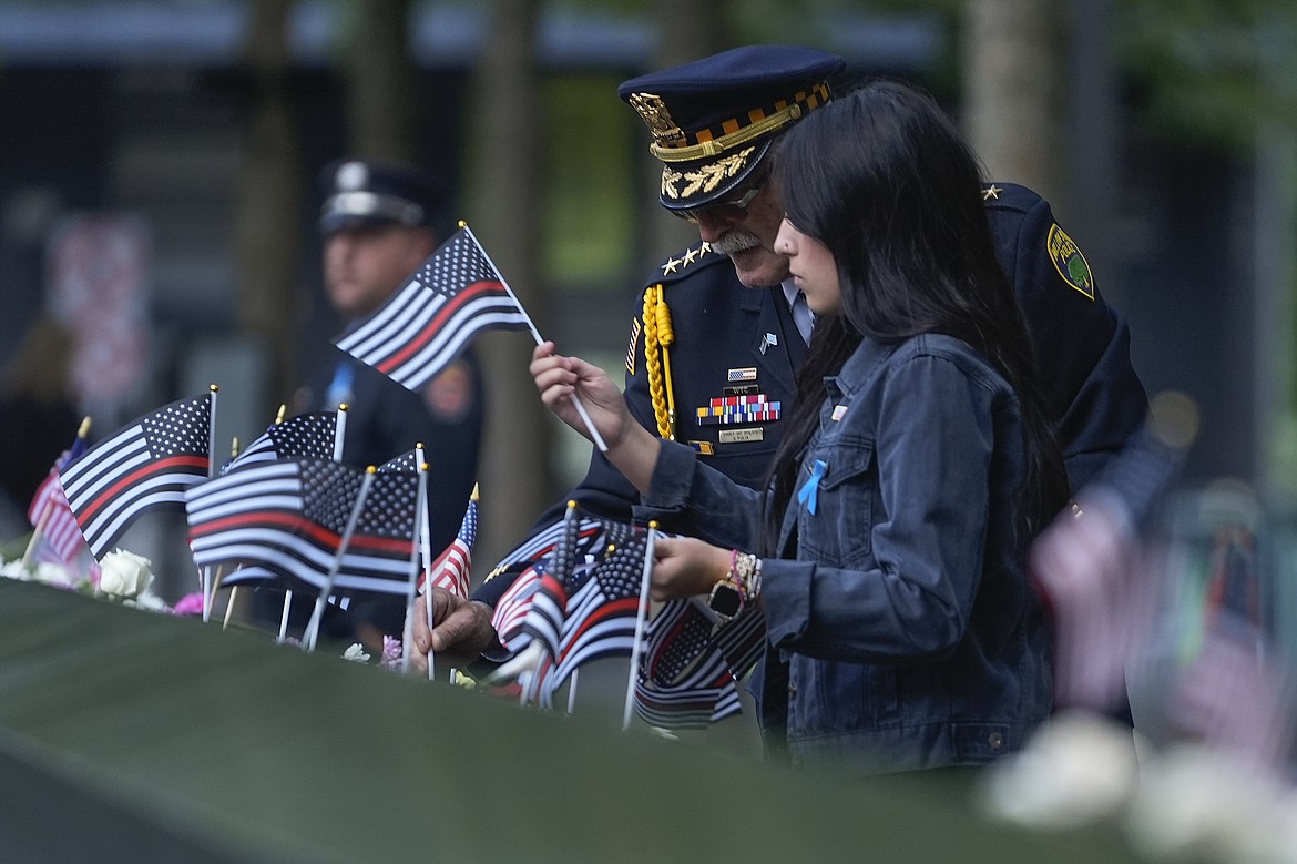 Sam Pulia, left, Willow Springs, Ill police chief, places flags on the bronze parapets at the 9/11 Memorial on the 23rd anniversary of the Sept. 11, 2001 terror attacks, Wednesday, Sept. 11, 2024, in New York. (AP Photo/Pamela Smith)