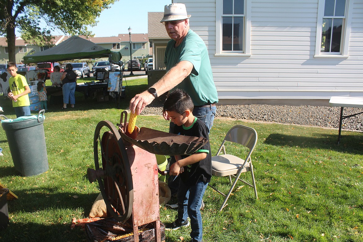 Rafael Farias, foreground, provides the horsepower and Steve Weber feeds the corn for the machine that separates the kernels from the cob at the 2022 Celebration of Cultures. This year’s celebration, which will give attendees a glimpse of pioneer life in the Quincy Valley, is Sept. 28.