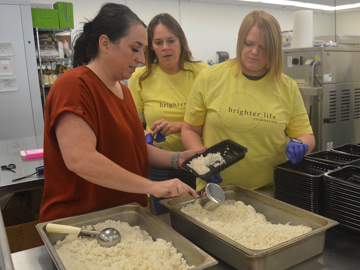 Desi Freeman, director of operations at Cōpow takes Brighter Life Foundation volunteers Shelby Bloxam and Lindsey Brahm through the meal assembly process.