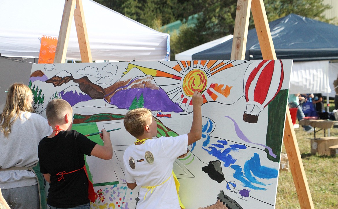 Attendees paint a landscape of Ponderay featuring the Selkirk Mountains, Lake Pend Oreille, and the Field of Dreams on Saturday.