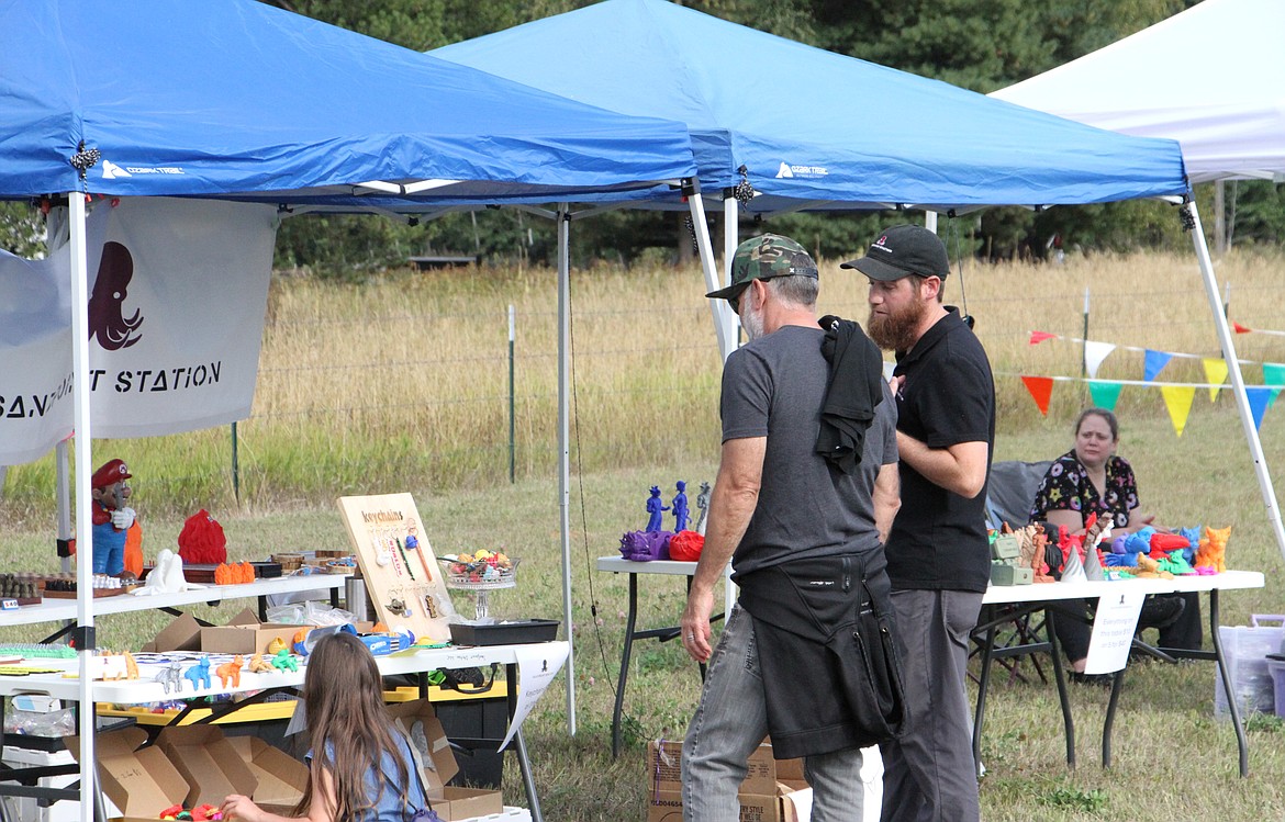 Sandpoint Station owner Ian Welton, pictured right, talks to a customer about his 3D-printed toys, game boards, and figurines.