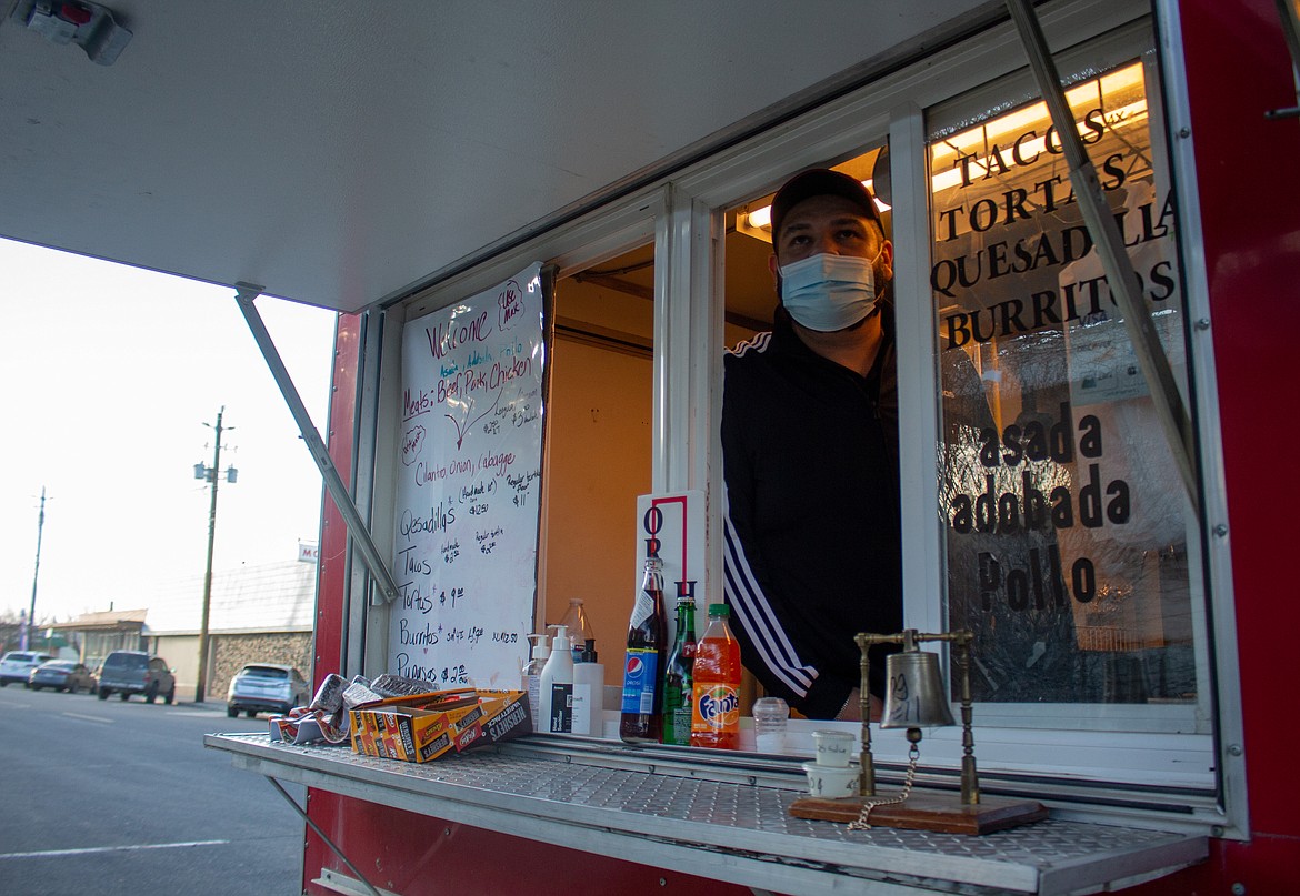 The owner of Quincy food truck looks at traffic while parked outside his brick-and-mortar restaurant in February 2021. The city has revised an ordinance by updating and reducing the restrictions on food truck operation in town.