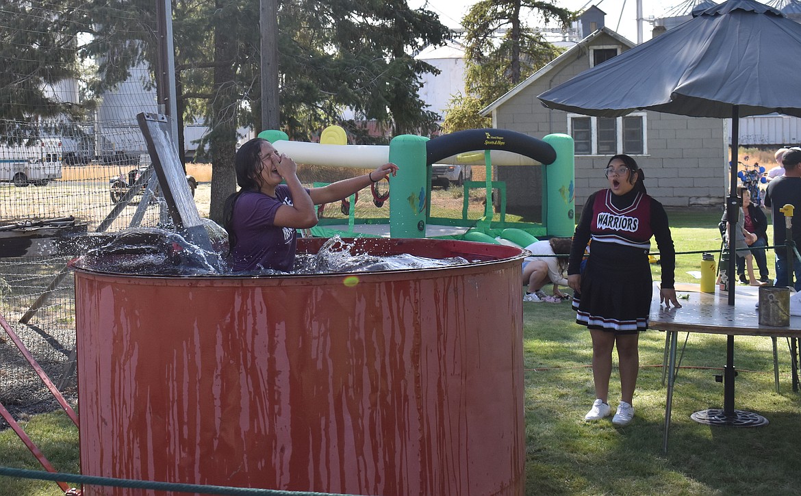 Almira/Coulee-Hartline High School student Dayana Mendoza drops into the dunk tank as her classmate Meryssa Gonzales watches in awe at Hartline Community Days Saturday. The dunk tank was one of several fundraisers to support scholarships for ACH students.