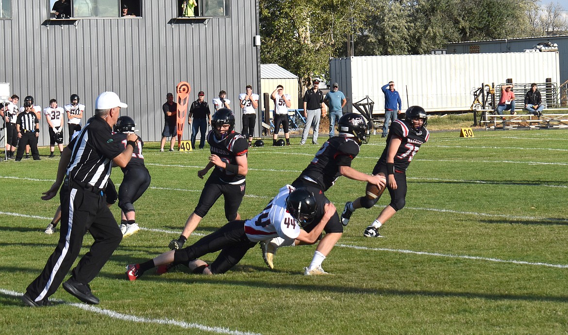 Almira/Coulee-Hartline quarterback Caden Correia, holding the ball, slips through an attempted tackle during Saturday’s game against Garfield-Palouse. Correia threw for 230 yards and four touchdowns in the win.