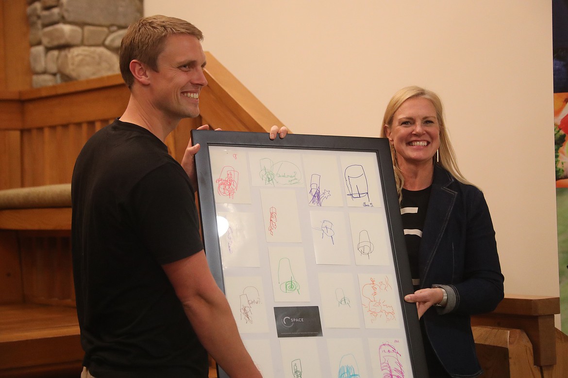 Matt Dethlefsen is presented a framed artwork creating by using contest entries from those attending Spacepoint's fall equinox celebration on Saturday. The goal of the contest was to draw an object of a Stoke Space rocket without looking down at the drawing and without lifting the pen from the paper.