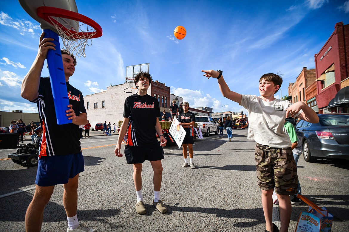 A boy shoots a basket on a toy hoop carried by members of the Flathead High School basketball team during the school's Homecoming Parade on Main Street on Wednesday, Sept. 18. (Casey Kreider/Daily Inter Lake)