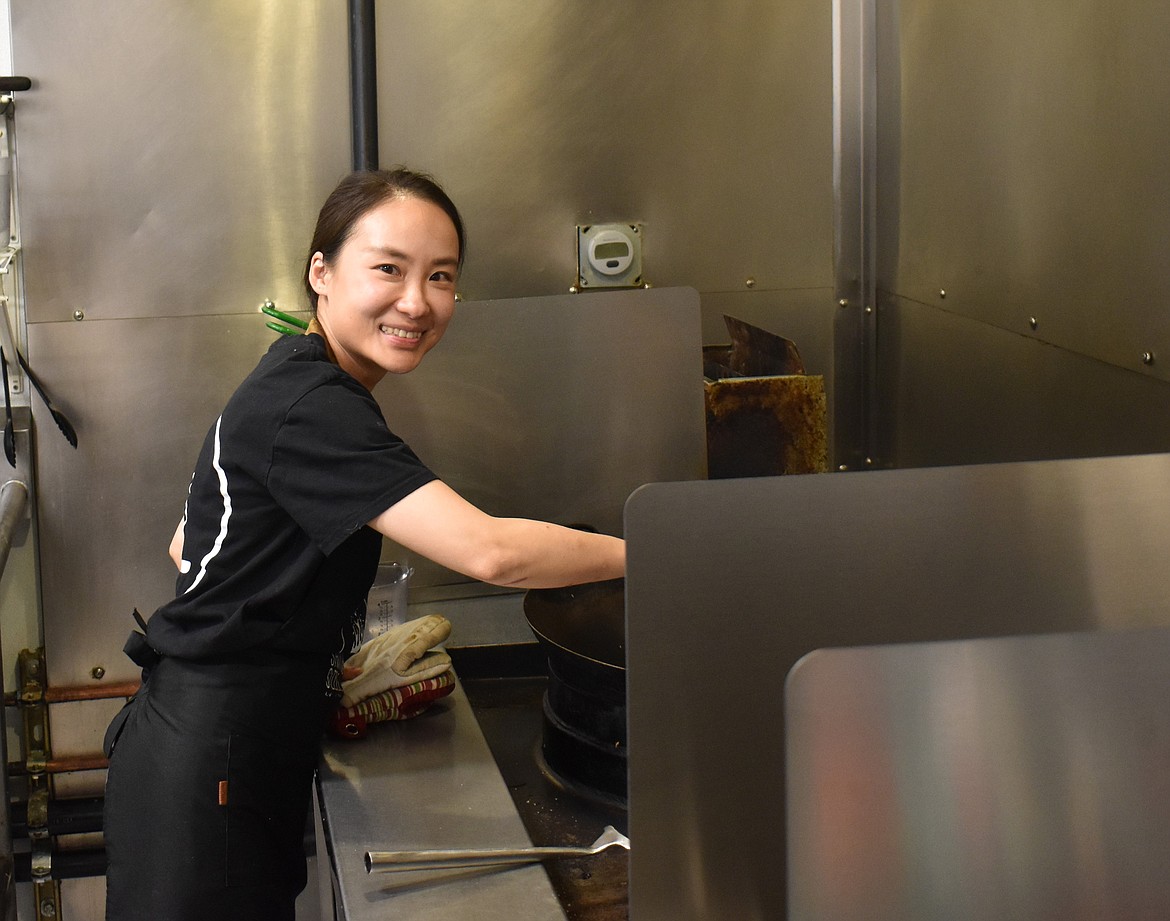 Chef Koey Pan stirs mushrooms, veggies and meat in a wok in the kitchen of Shiitake Sizzle, which she owns with partners Dahlia O’Neil and Iris Ou.