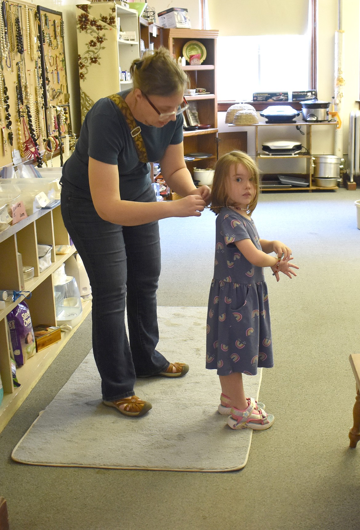 Four-year-old Lisette Heidenthal of Wilbur tries on a necklace she’s found at the Hartline Second Hand Mall, with a little help from her mom Kristen Heidenthal. Kristen has a background in museums and historic preservation, she said, so she’s always wanted to visit the Hartline school, and hearing of a chess set for sale there gave her the opportunity.