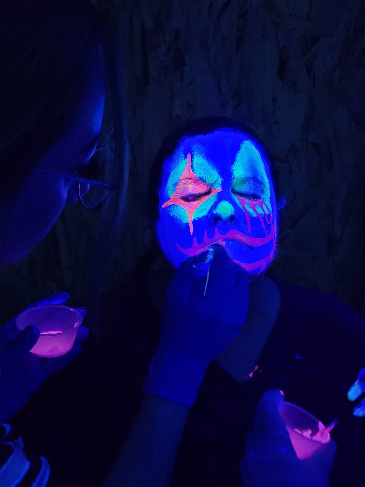 Karen Pixler gets clown makeup done under a black light Sept. 13 during a Scarywood training night. The Halloween haunt opens for the season Friday at Silverwood Theme Park.