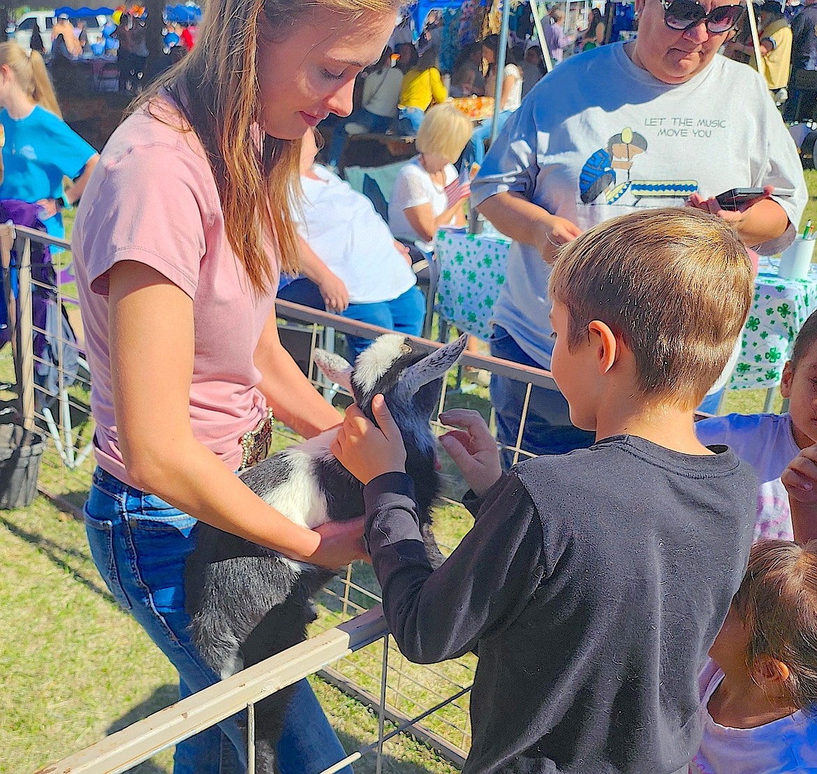 Saddle Mountain 4-H member Lilia Mitchell holds a baby Nigerian Dwarf goat so children can give him a pat at the club's petting zoo. (Berl Tiskus/Leader)