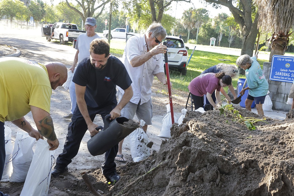 Karl Bohlmann, left, and Tangi Bohlmann, of Tarpon Springs, collect sandbags at a public site while residents prepare their homes for potential flooding, Tuesday, Sep 24, 2024, in Tarpon Springs, Fla., as the Tropical Storm Helene approaches. (Douglas R. Clifford/Tampa Bay Times via AP)