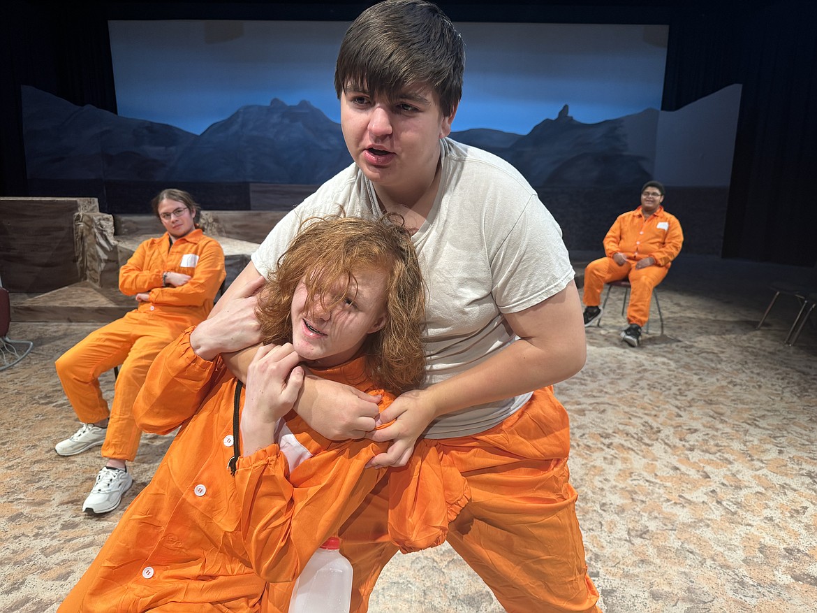 In a Glacier Wolfpack Theatre production of "Holes," veteran inmate, Armpit, played by Ethan Lopez, puts Stanley, played by Fenyx Colby, in a headlock while X-Ray, played by Tregan Blades and Magnet, played by Theron Wilton watch the show. (Courtesy image)