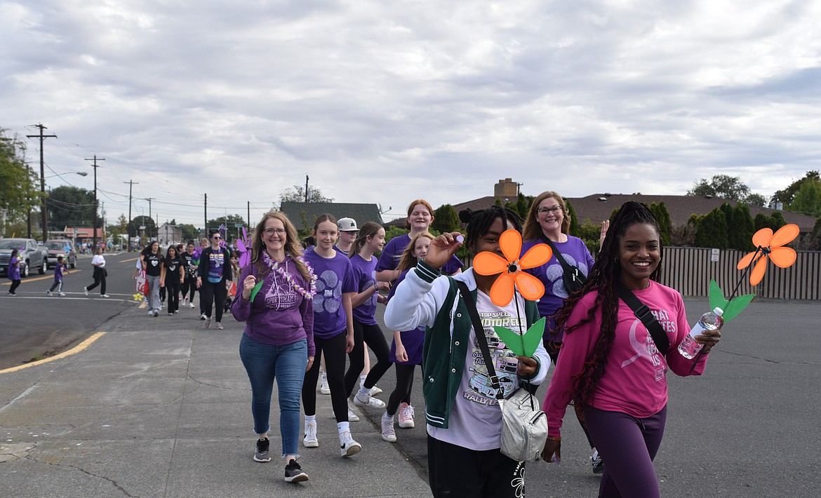 Members of the Walk to End Alzheimer's round back to McCosh park on Saturday to finish the walk. People with blue flowers are living with Alzheimer's or dementia. Purple flowers represent someone lost to the disease. Yellow represents someone who is caring for someone living with Alzheimer’s. Orange is for those who support the cause.